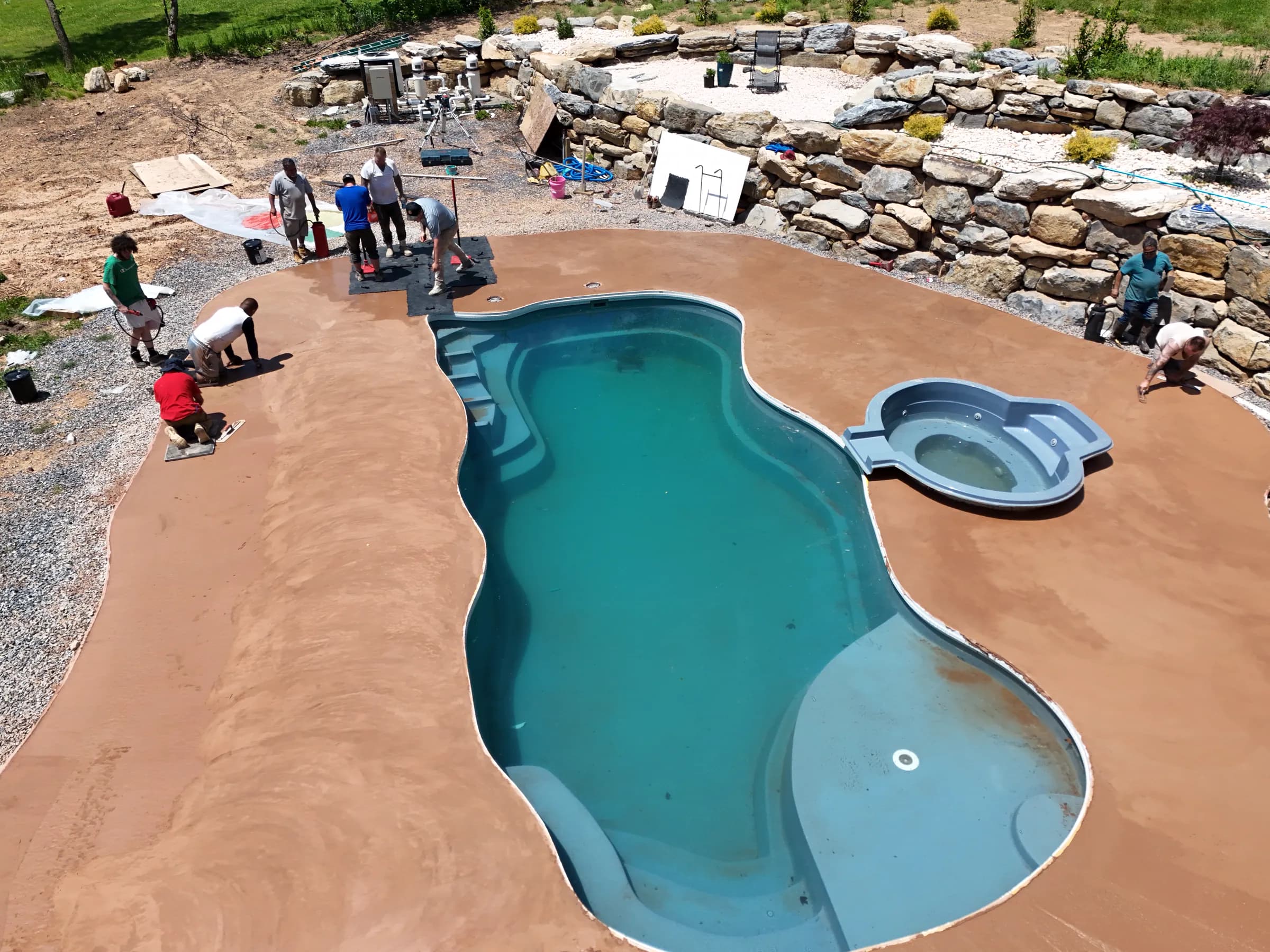 Overhead progress photo of a crew finishing the deck around a new backyard pool
